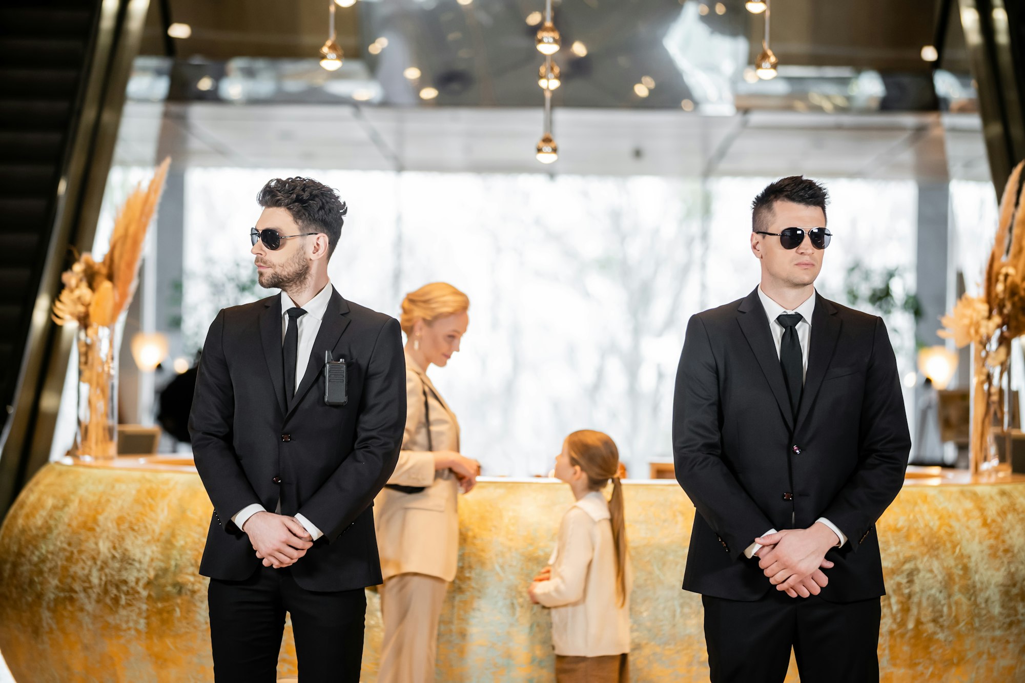 personal security, handsome bodyguards in suits and sunglasses protecting mother and child in hotel